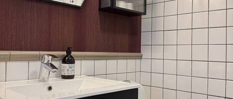 A bathroom with a white sink, black cabinet, and a mirror.