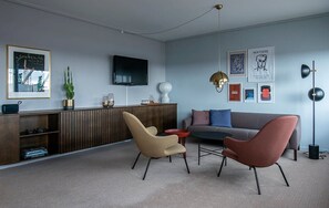 A modern living room with a sofa, two chairs, a coffee table, a TV, and artwork on the walls. - Hotel Jutlandia (Frederikshavn)
