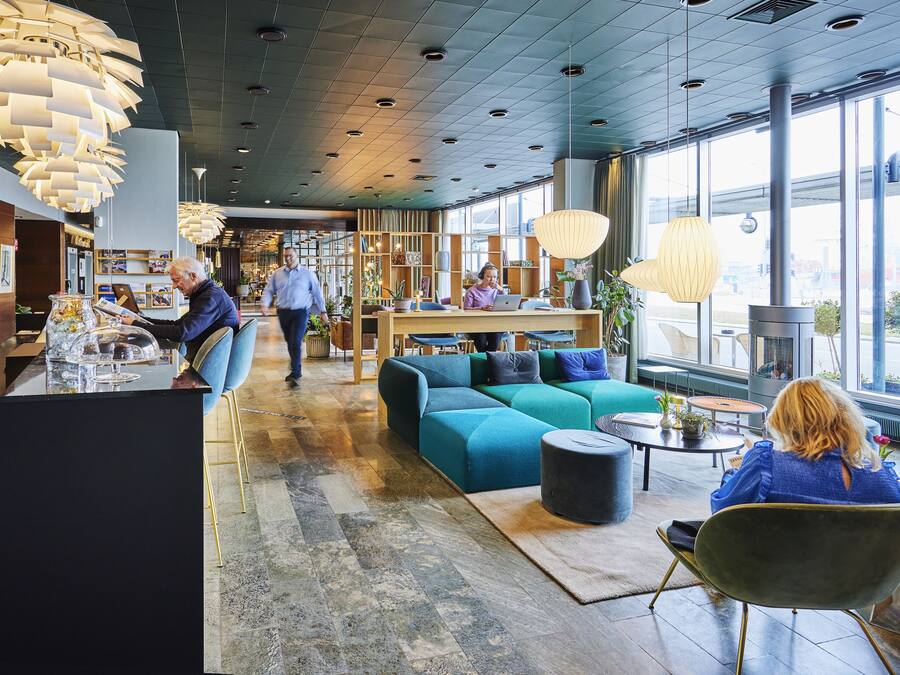 A modern interior with a reception desk, seating area, and large windows offering views of the outside.