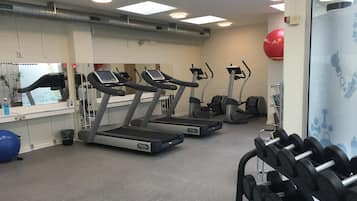 A gym with treadmills, a wall-mounted exercise ball, and a rack of dumbbells.