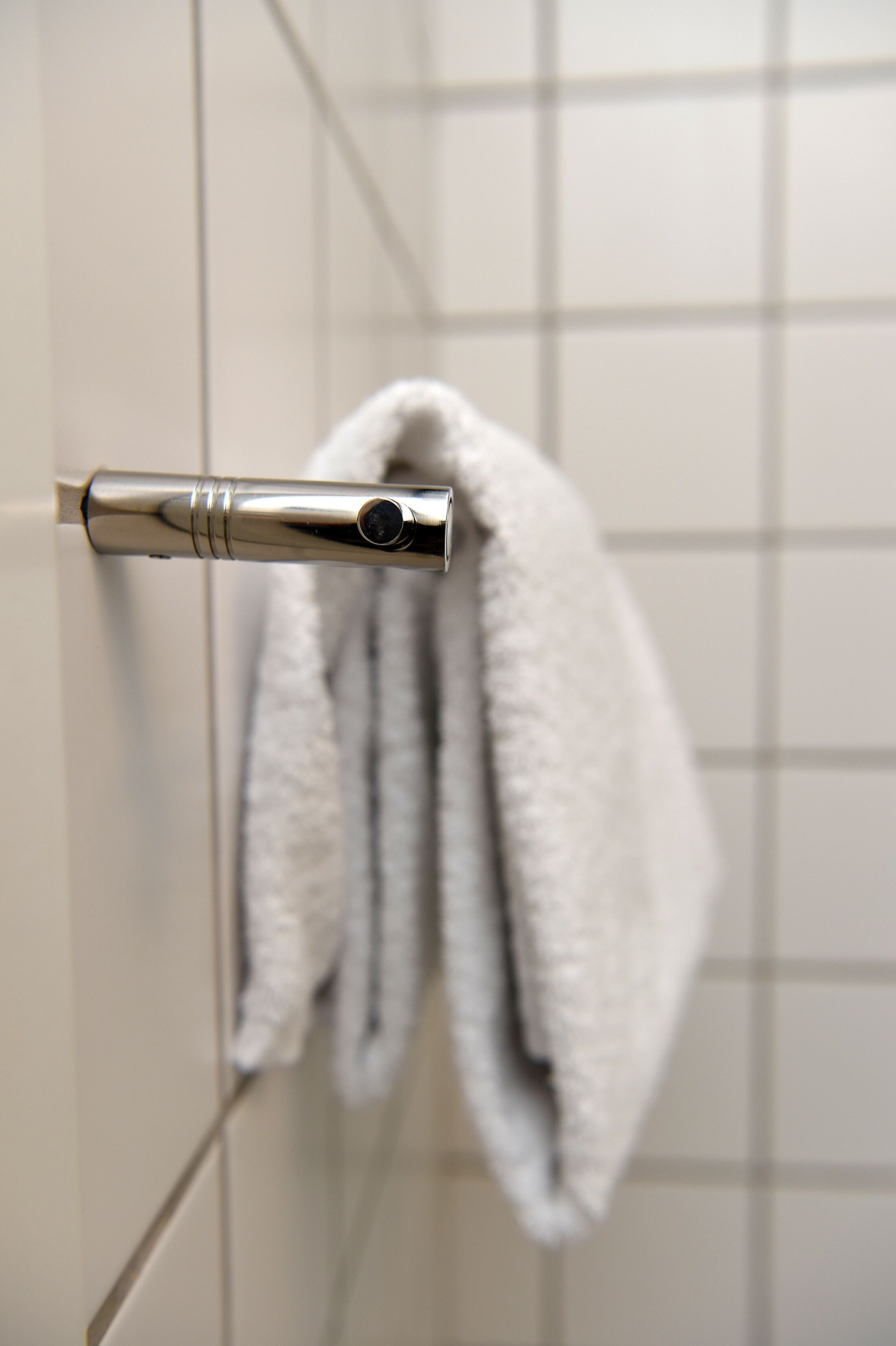 A bathroom with a towel hanging on a metallic towel rack.