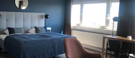 Una habitación de hotel con cama, una silla, un escritorio y ventana.