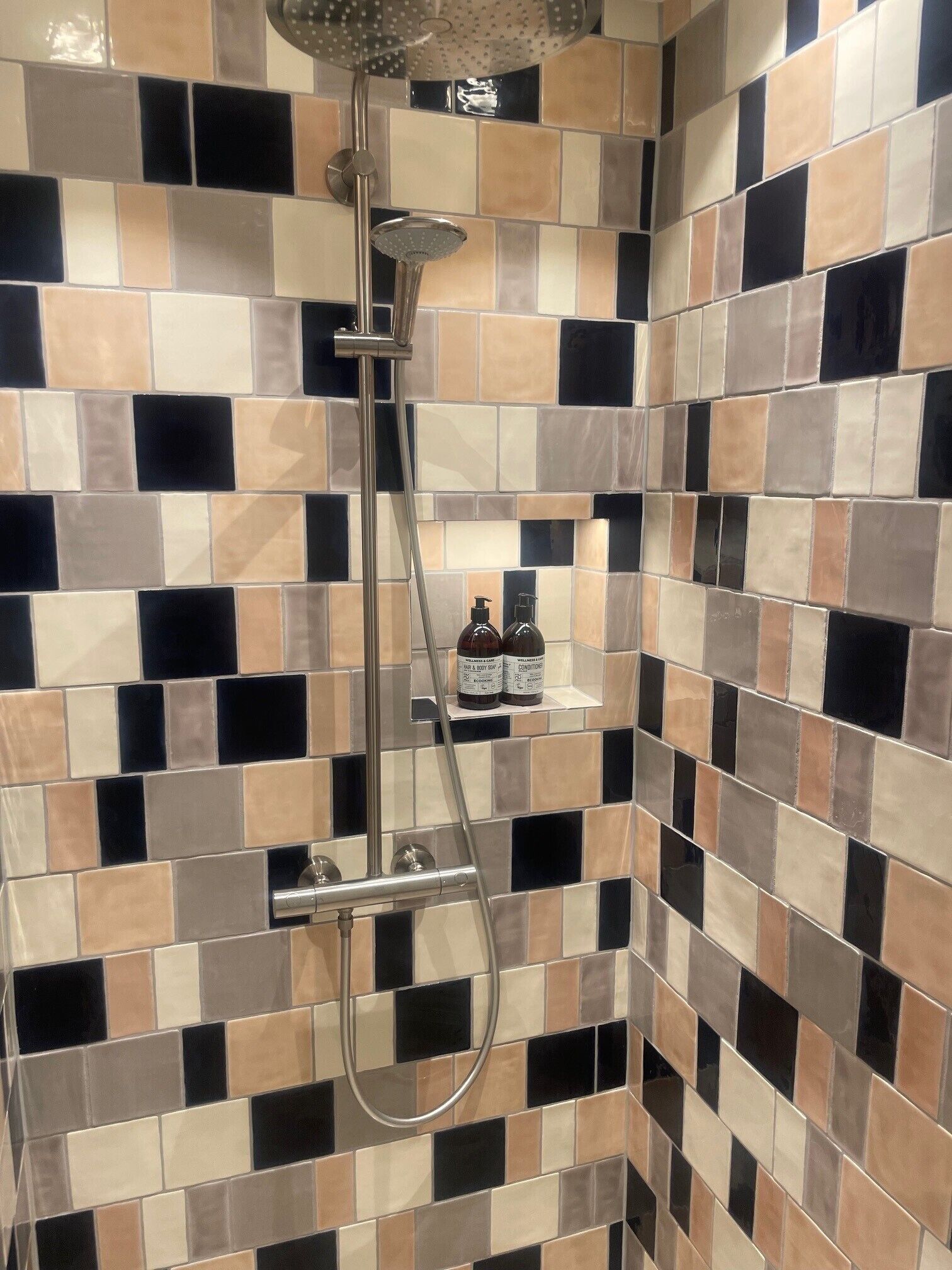 Un baño con pared de ducha azulejada y ducha de mano.