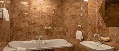 A bathroom with a large bathtub, a sink, and a mirror.