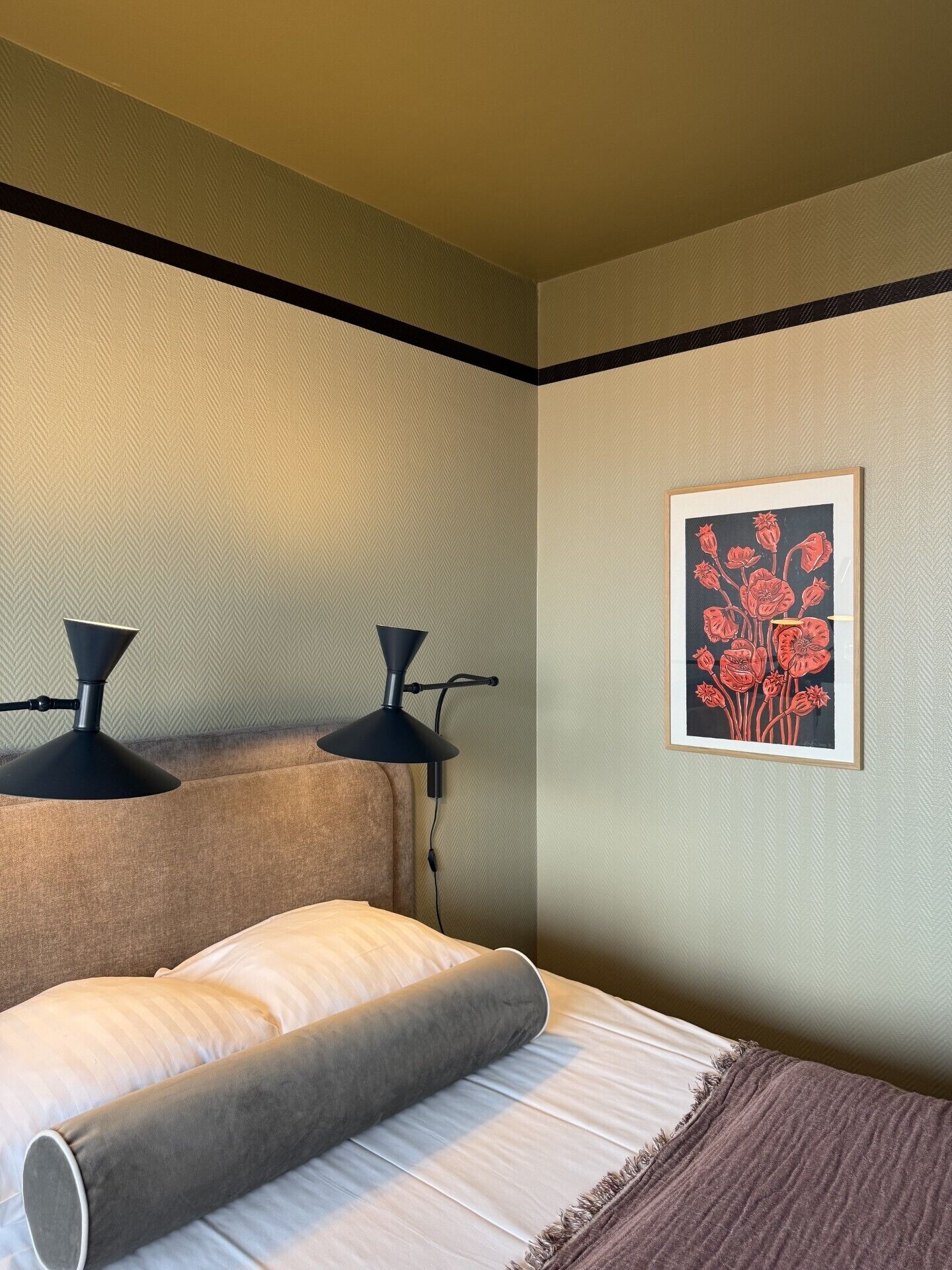 Une chambre à coucher avec un lit, deux lampes de chevet, une œuvre d’art accrochée au mur et un mur à texture.