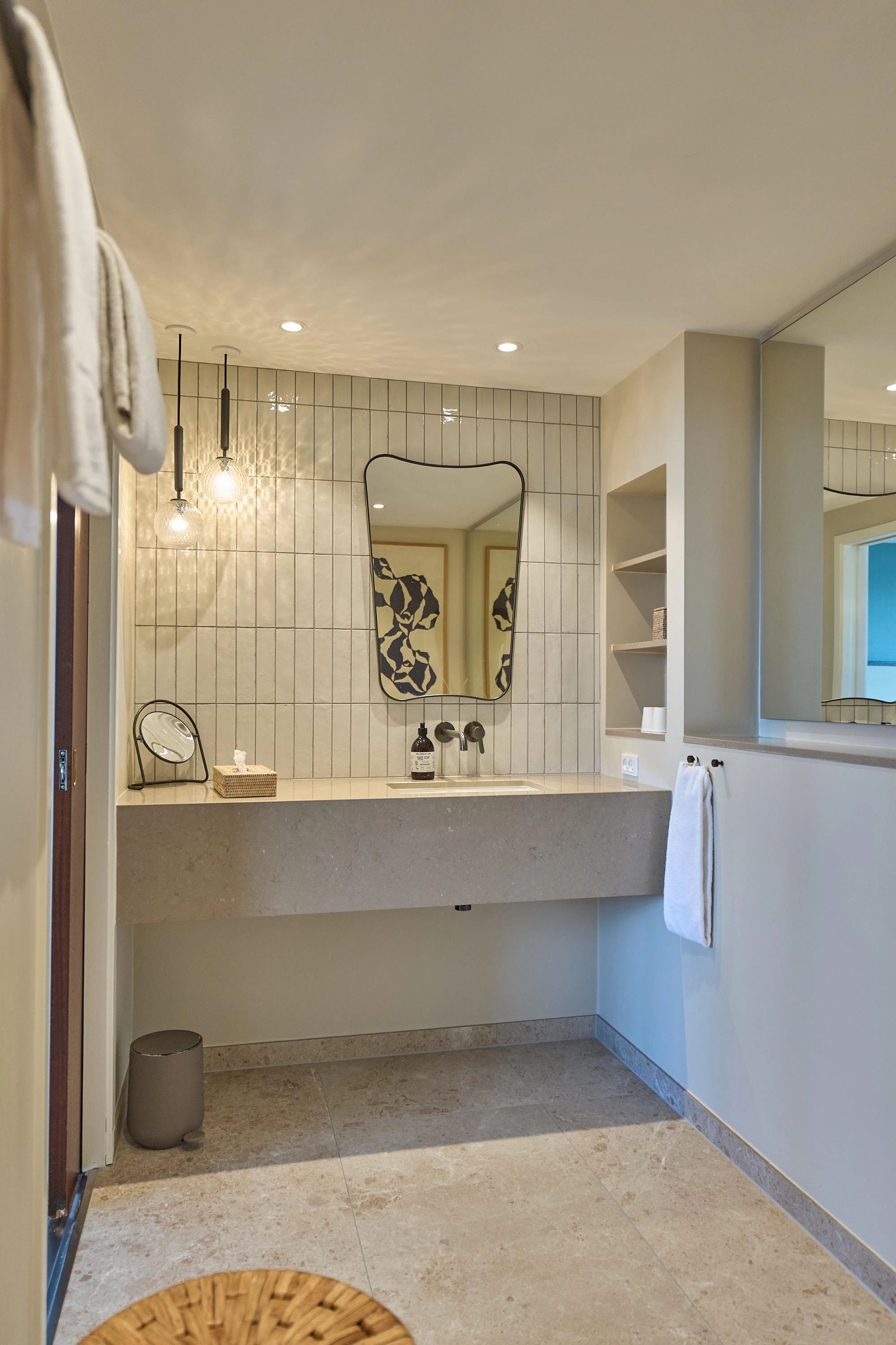 A bathroom with a large mirror, a towel rack, a sink, and a toilet.