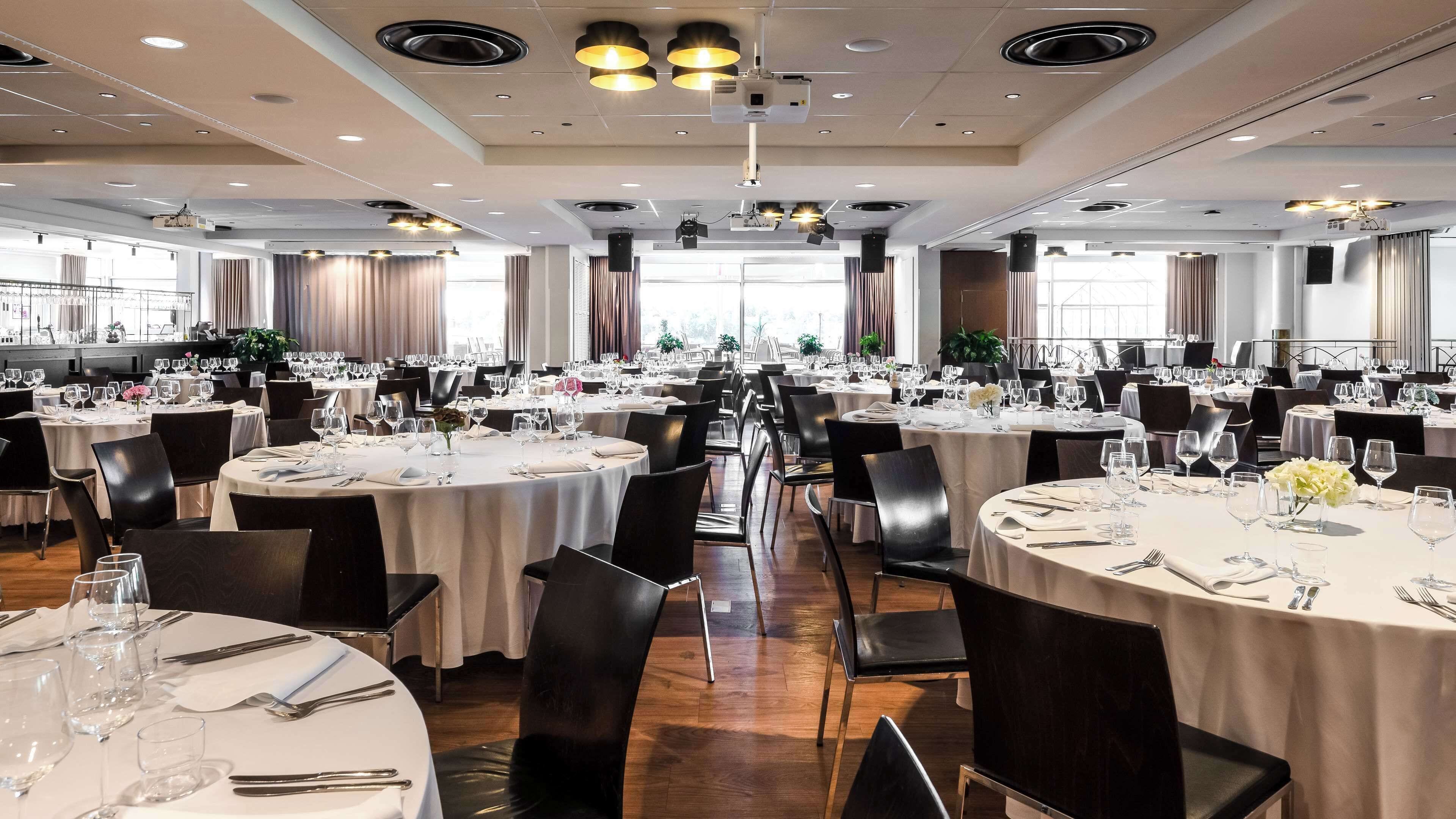 A large banquet hall with round tables set for dining, equipped with chairs, tables, and dining ware.