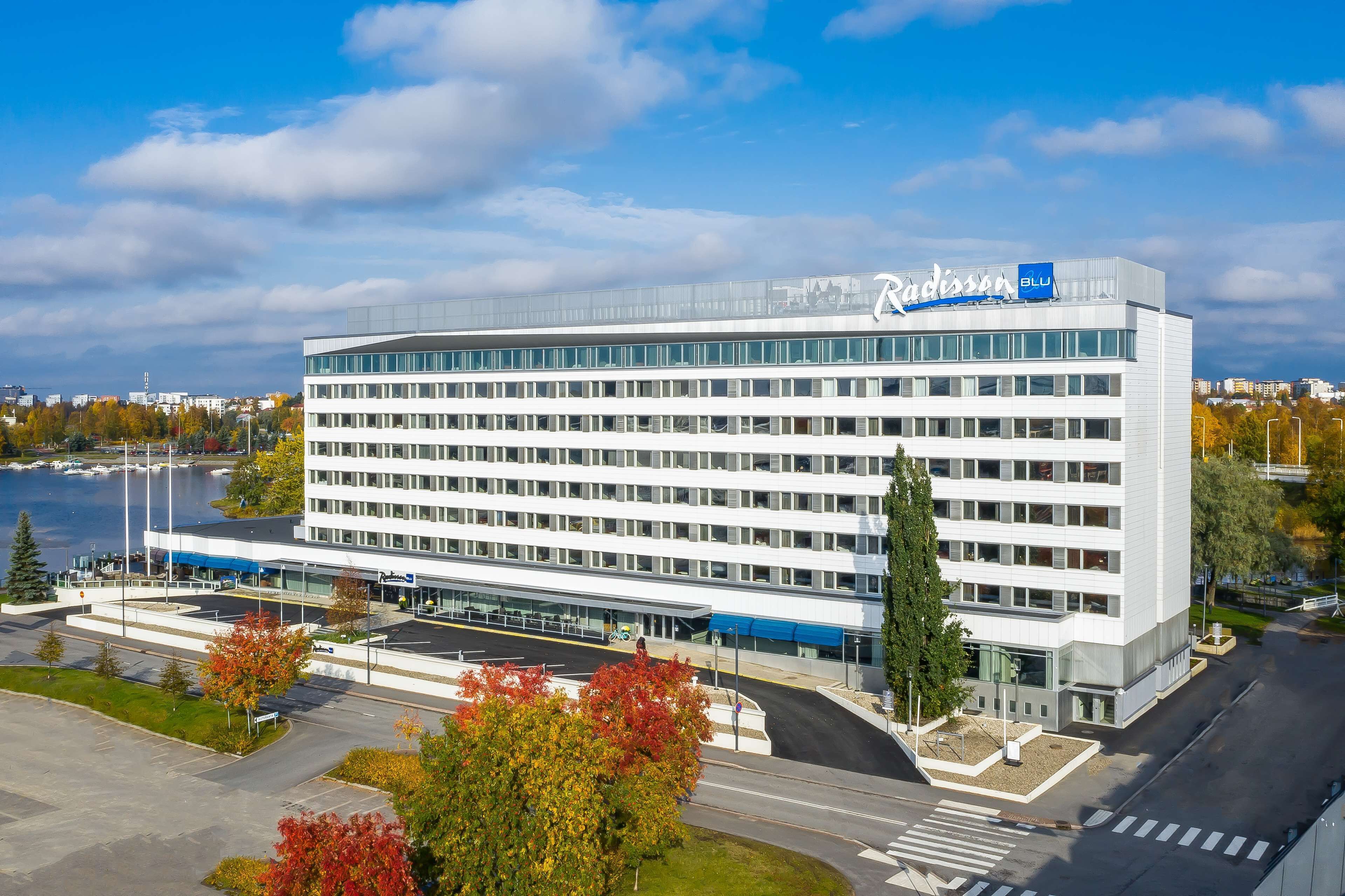 Ein modernes Hotel mit flachem Dach, großen Fenstern und einem Schild mit der Aufschrift 'Radisson Blu'.