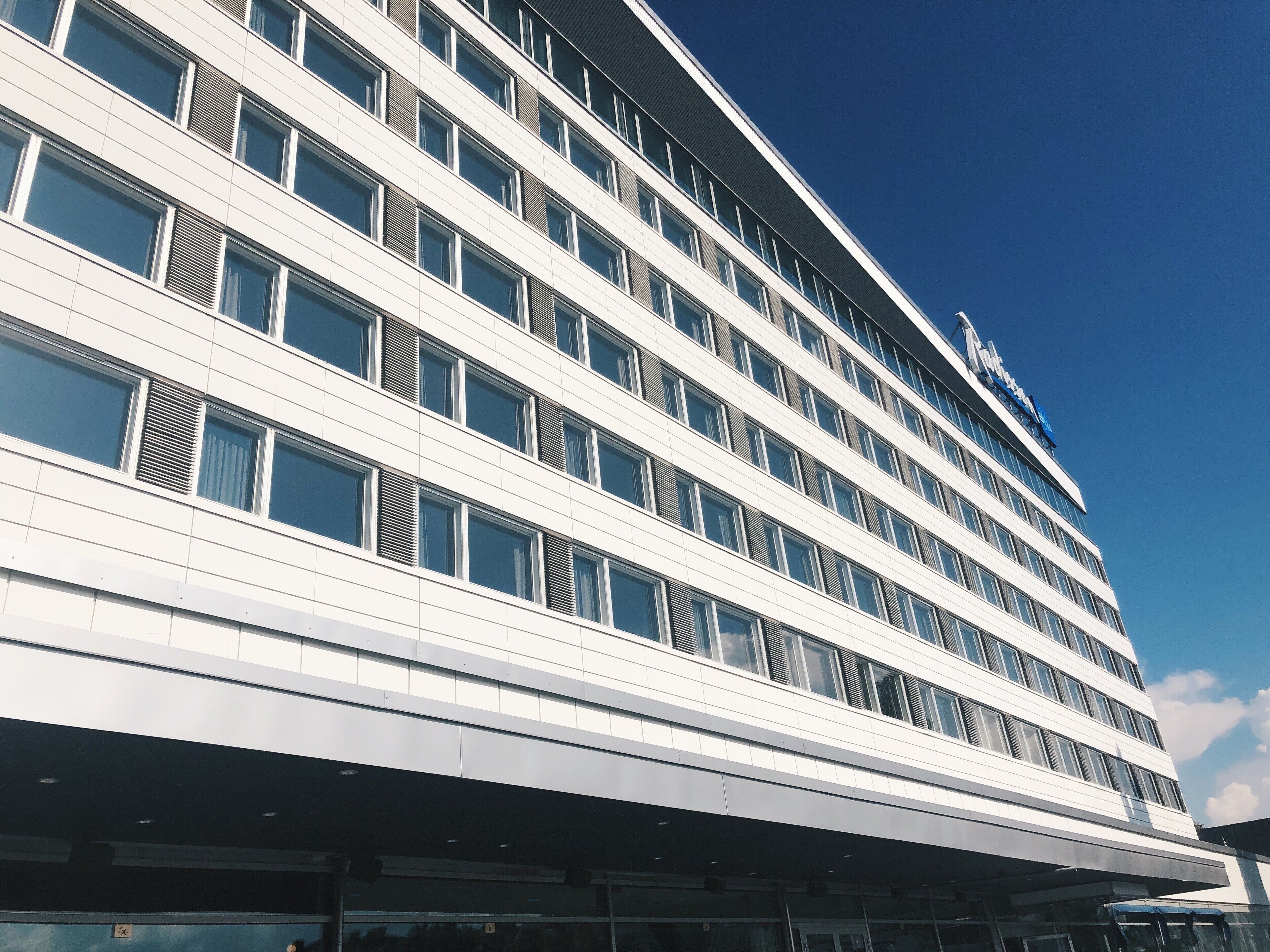 Un hotel moderno a più piani con facciata lineare, ampie finestre e un cartello ben visibile in cima.
