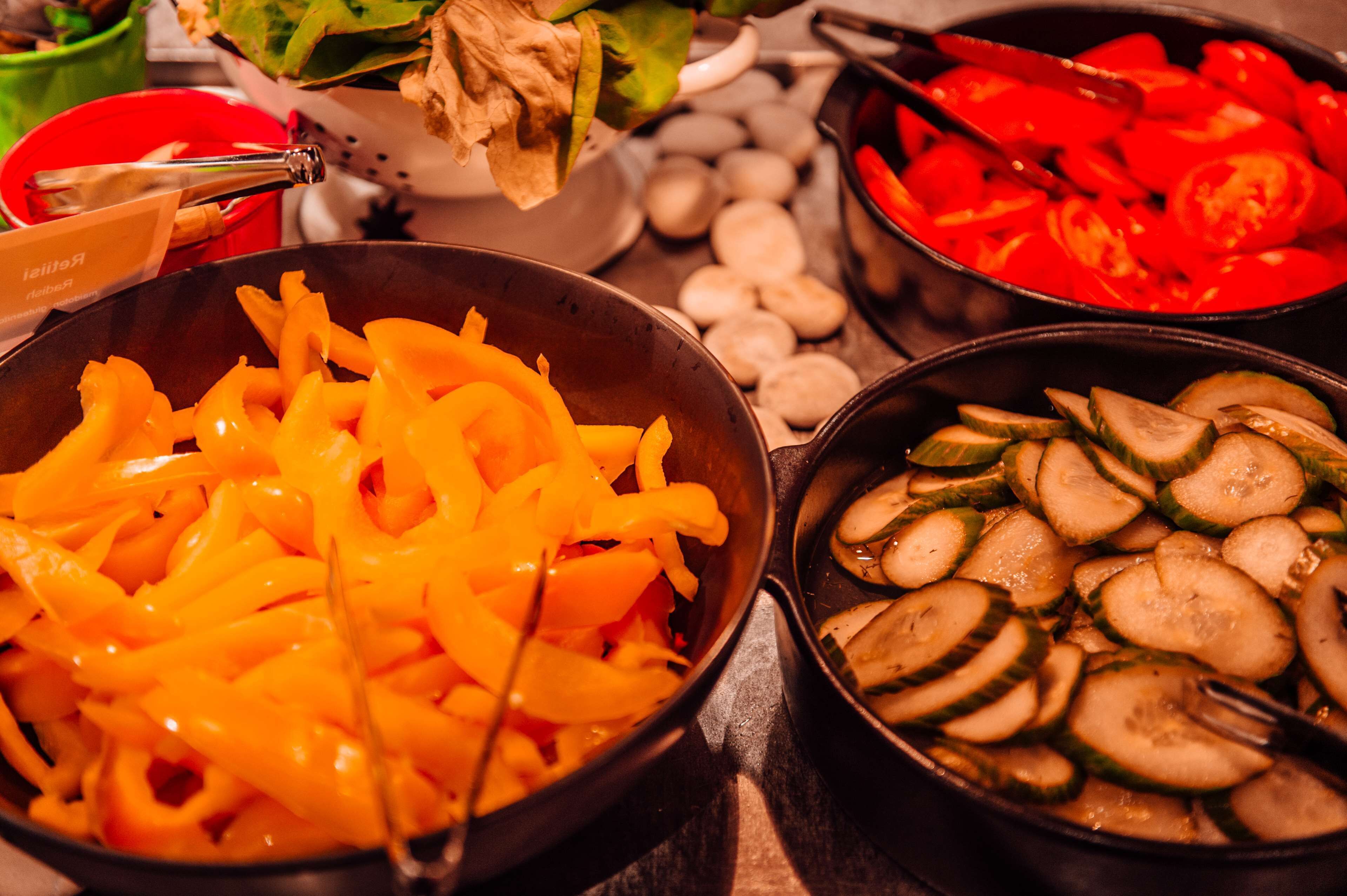 Un assortiment de légumes coupés en tranches, notamment des carottes, des courgettes et des tomates, présentés dans des bols séparés.