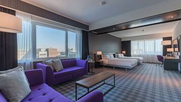 Habitación de hotel con una cama grande, un sofá, un escritorio y vistas a la ciudad.