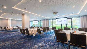 A conference room with tables and chairs, a projector screen, and large windows.