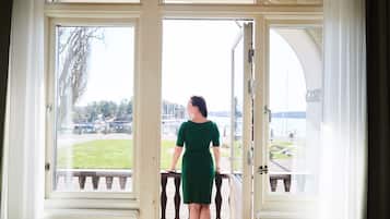 Une femme se tient devant une porte vitrée, avec vue sur une zone herbeuse et un bâtiment en arrière-plan.