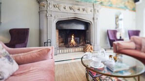 Ein gemütliches Wohnzimmer mit Kamin, bequemen Sitzmöglichkeiten und einem Glastisch.