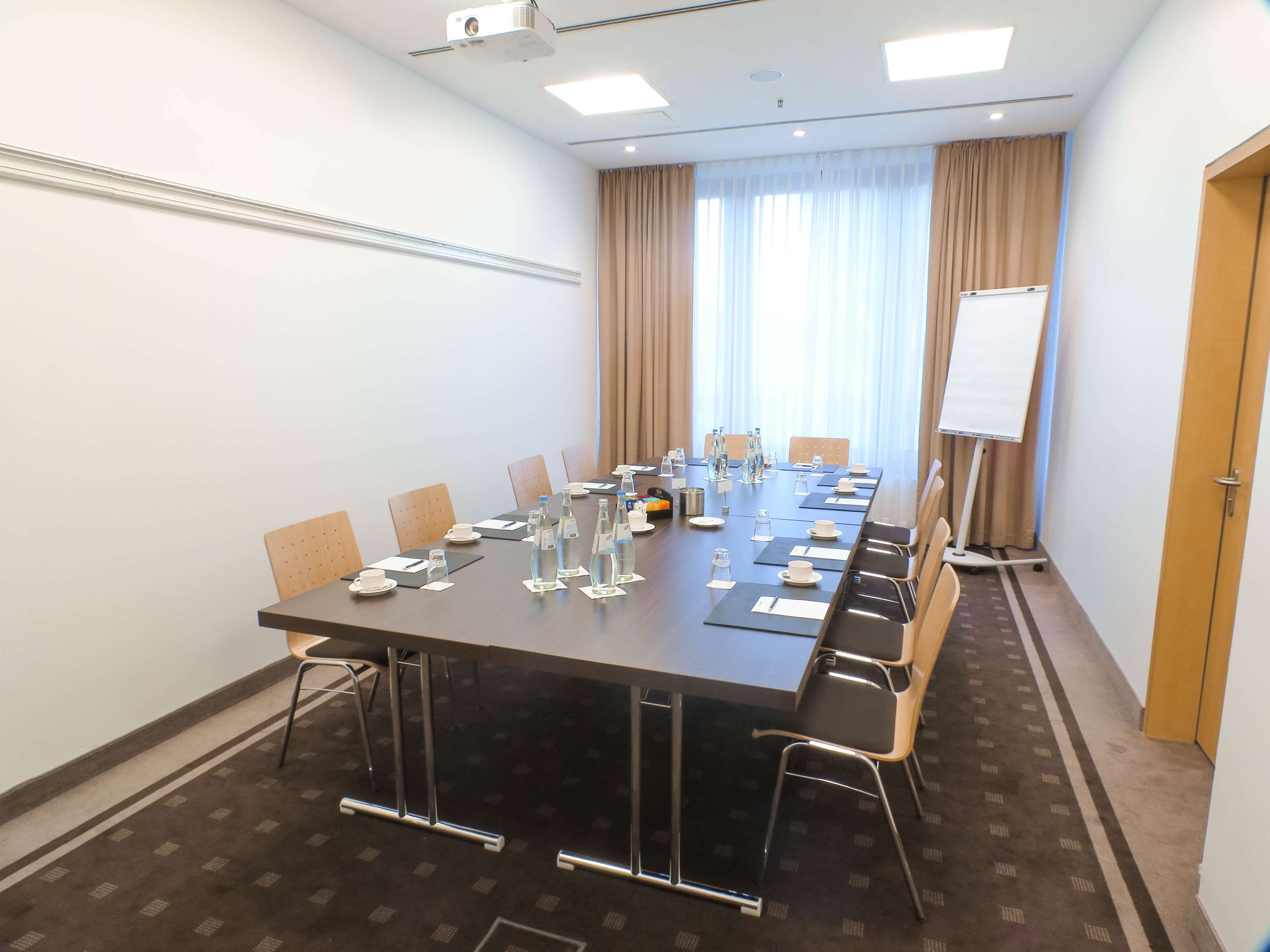 A conference room with a long table, chairs, water bottles, and a whiteboard.