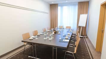 Un salón de conferencias con una larga mesa, sillas, botellas de agua y una pizarra.