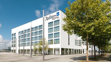 Ein Radisson Blu Hotel mit zeitgemäßem Fassadengestaltung, großen Fenstern und einem gepflasterten Eingangsbereich.