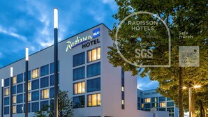 Hotel Radisson con fachada moderna, varios pisos y ventanas iluminadas.