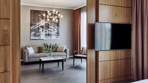 Una sala de estar moderna con un sofá, un sillón, una mesa de centro y un televisor de pantalla plana montado en una pared de madera.