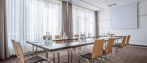 A conference room with a long table, chairs, a projector, and a whiteboard.