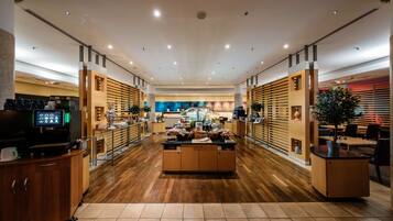 Un amplio vestíbulo de hotel con una recepción central, suelo de madera y un diseño moderno.