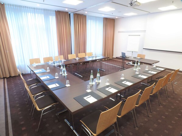 A conference room with a long table, chairs, water bottles, and a projector screen.