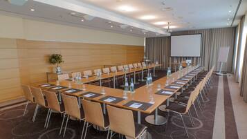 A conference room with a long table, chairs, water bottles, and a projector screen.