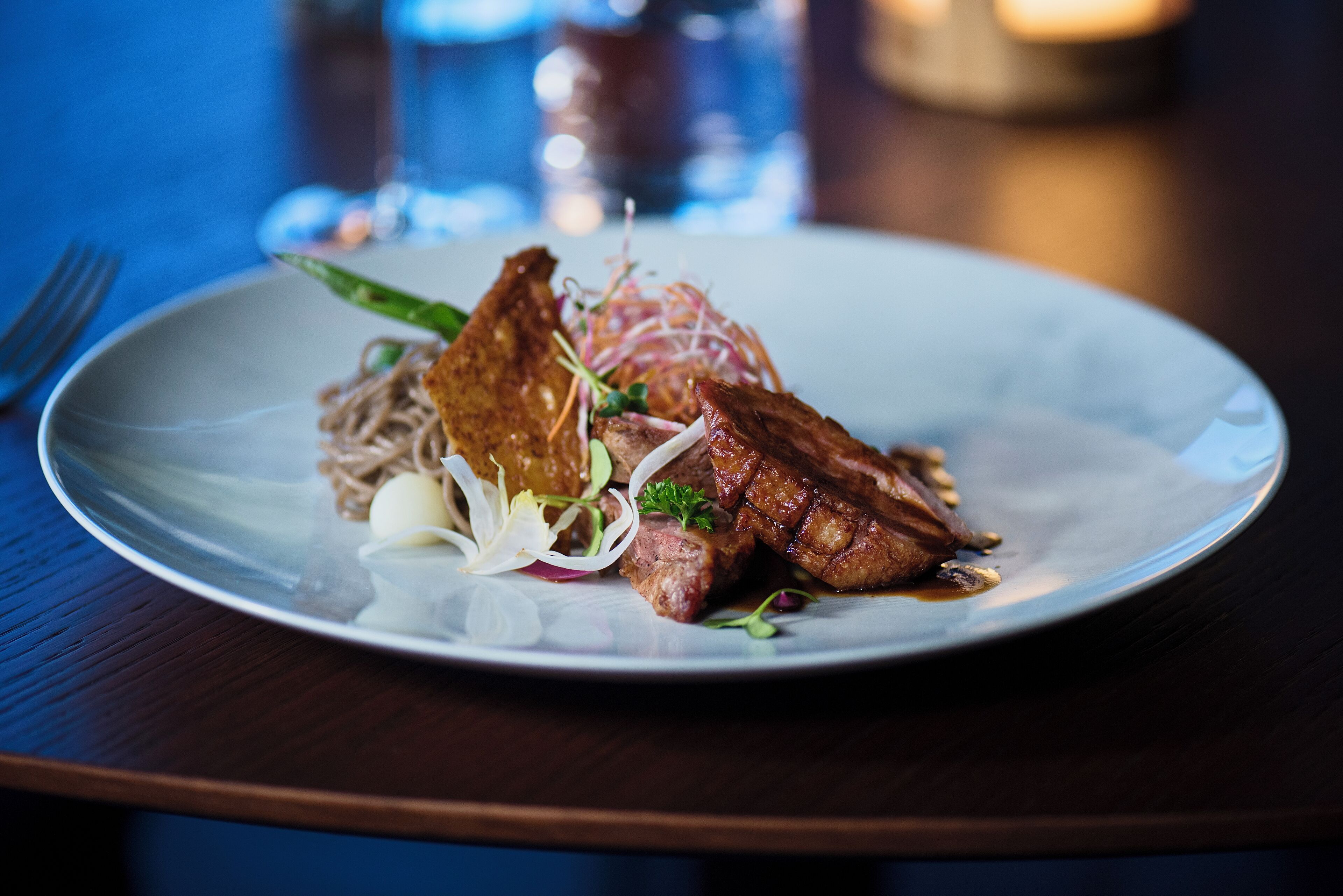 Lautasella on nuudeleita, lihaa ja kasviksia, ja lautanen on valkoinen.
