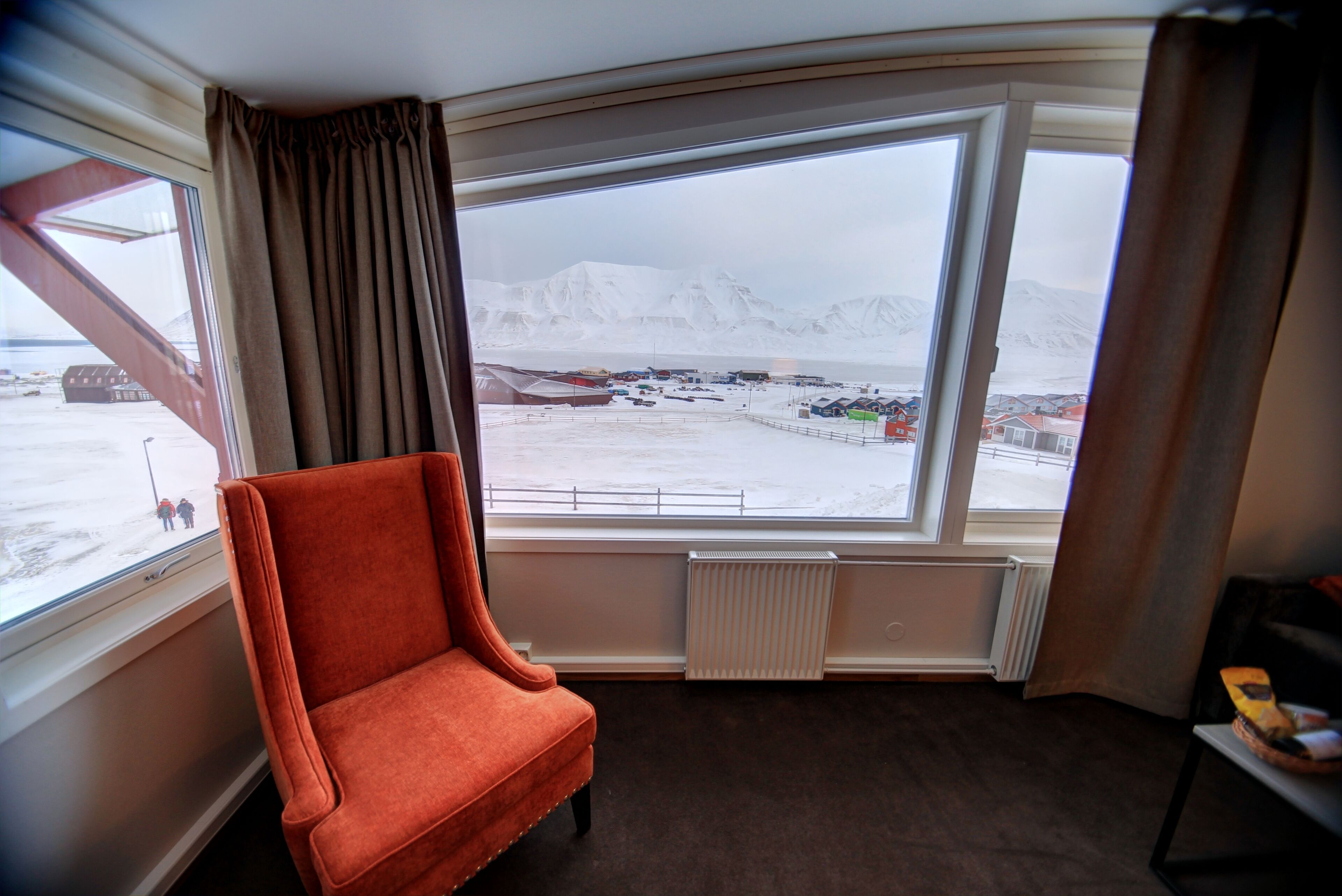 A room with a large window offering a view of a snowy landscape and mountains.