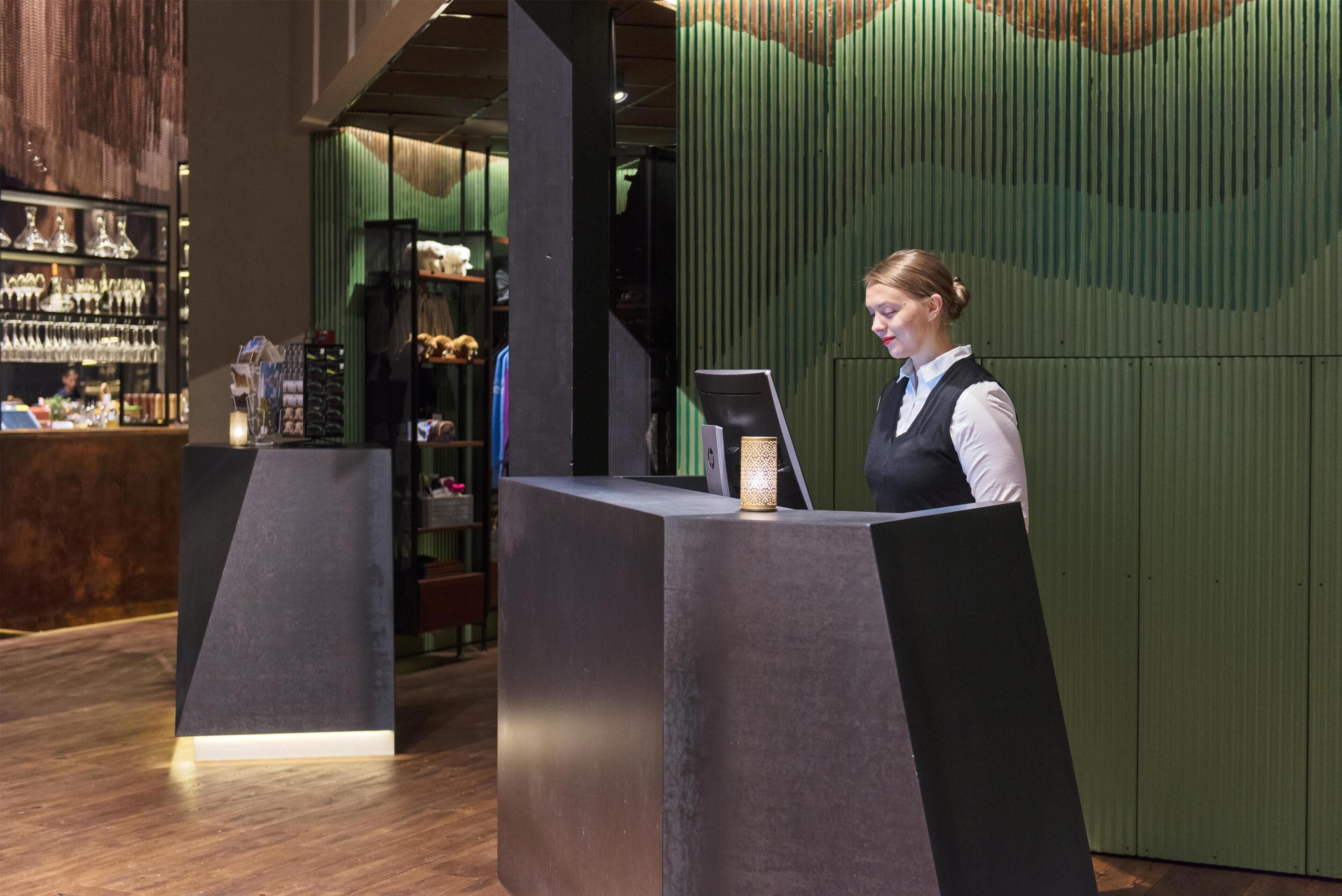 A reception desk with a modern design, a computer, and a small table with a lamp.