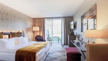 A hotel room with a bed, a desk, a chair, a TV, and a view of the outdoors.