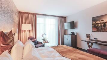 Une chambre d’hôtel avec un lit, un bureau, une télévision et une fenêtre avec des rideaux.