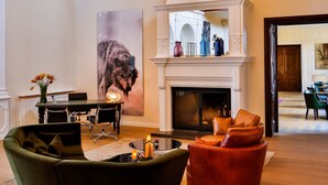 Een ruime woonkamer met een open haard, een hoog houten plafond en een trap die naar een verdieping leidt.