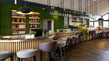 A modern bar with a green wall, wooden accents, and bar stools.