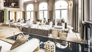 Een moderne zithoek met witte banken, een marmeren salontafel en decoratieve vazen.