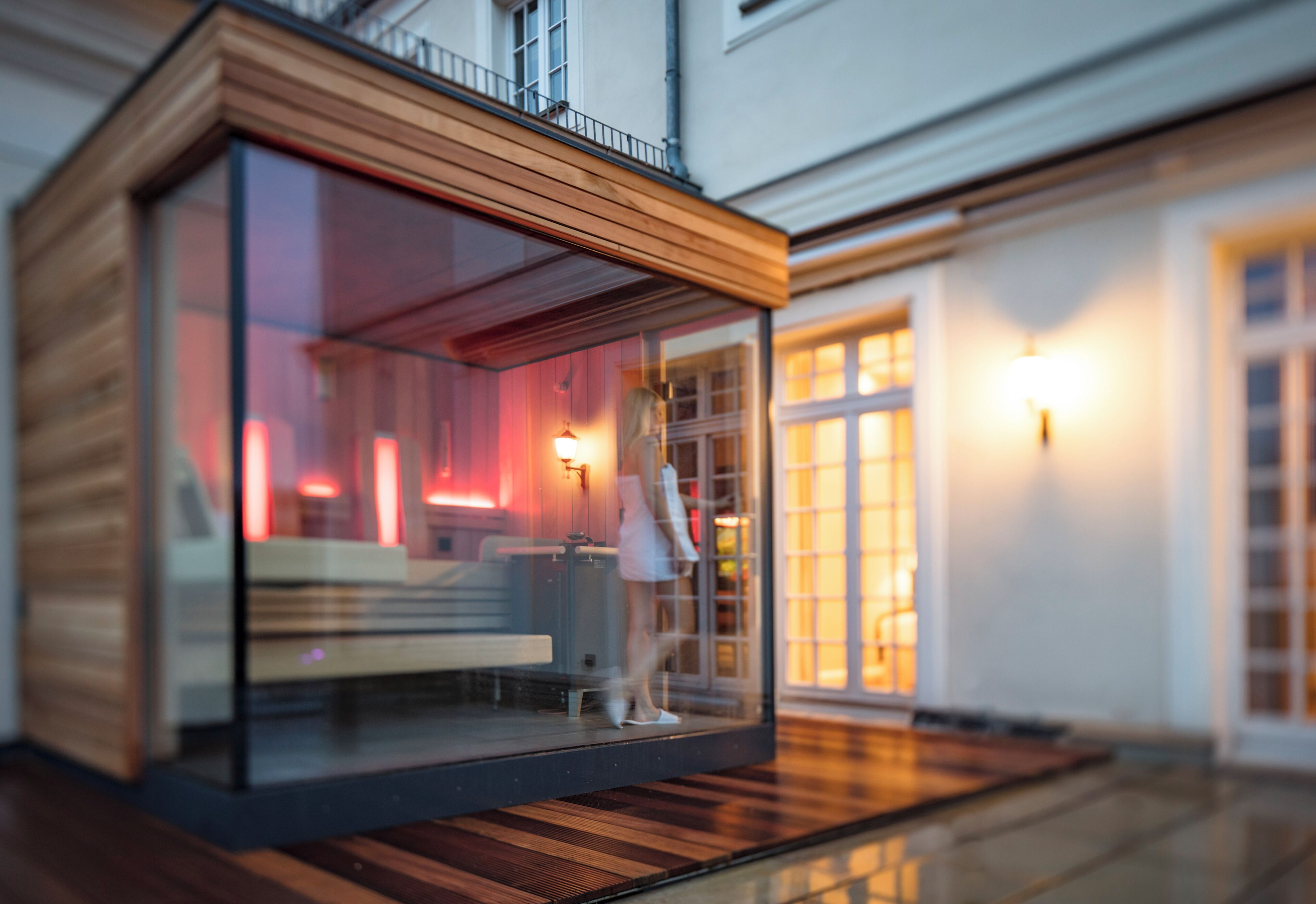 Une structure moderne en verre, dotée d’un revêtement extérieur en bois, d’un banc et d’une rambarde.