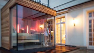 Une structure moderne en verre, dotée d’un revêtement extérieur en bois, d’un banc et d’une rambarde.
