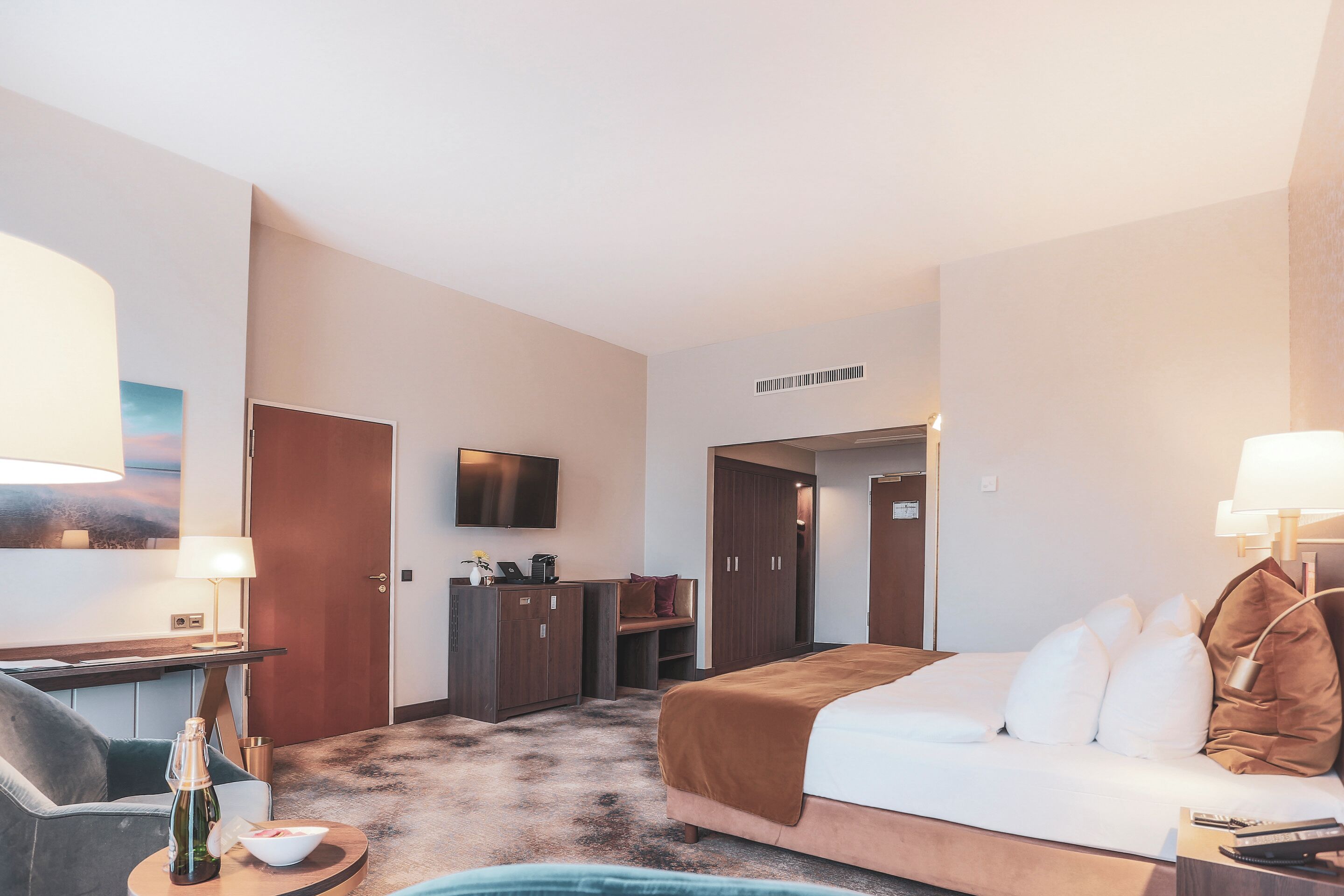 Una camera d'albergo con un letto, una scrivania, una televisione e un armadio.