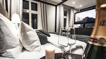 Ein Hotelzimmer mit einem Bett, einem Fernseher, einer Champagnerflasche und zwei Gläsern.