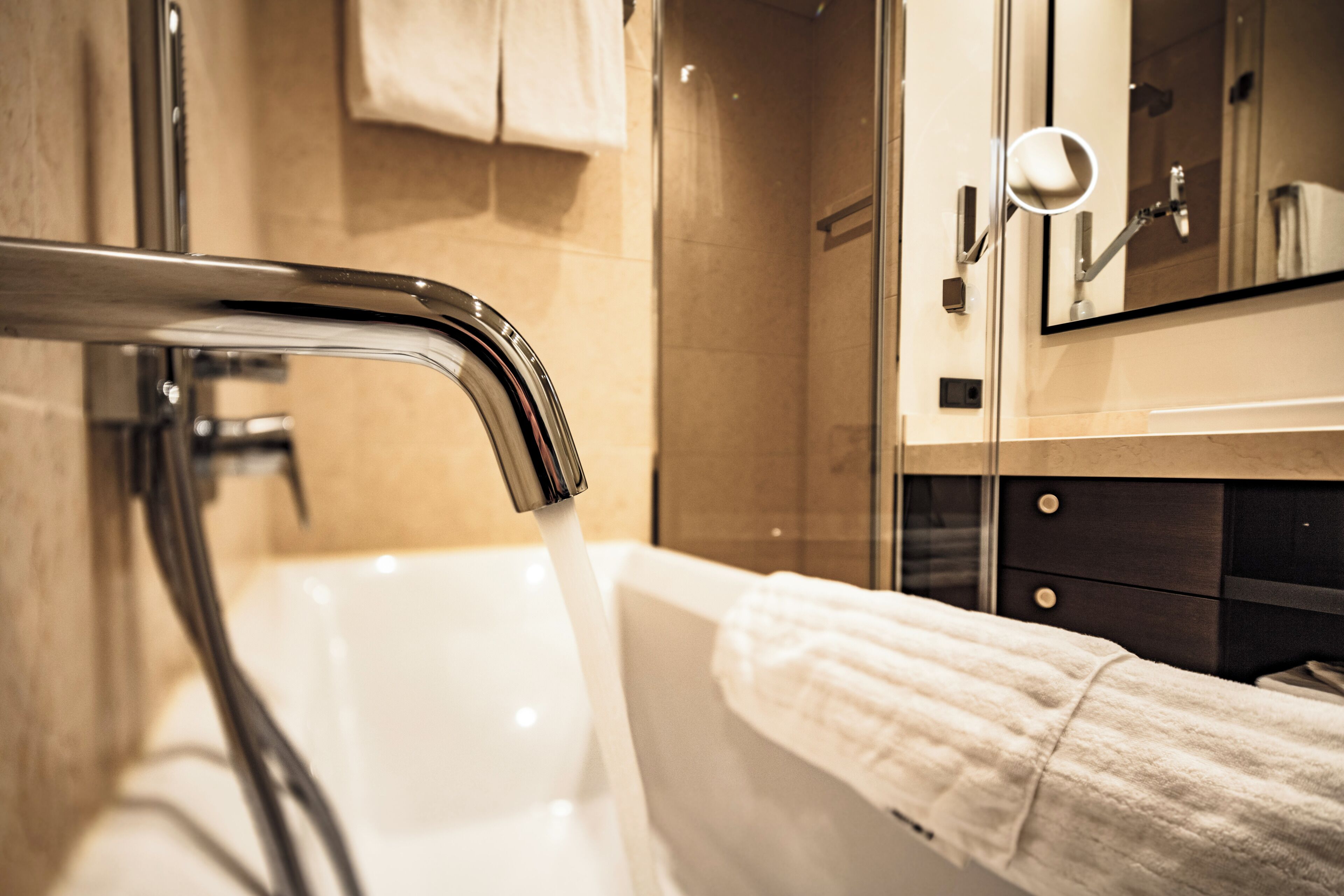 Een moderne badkamer met een bad, douche en spiegel.