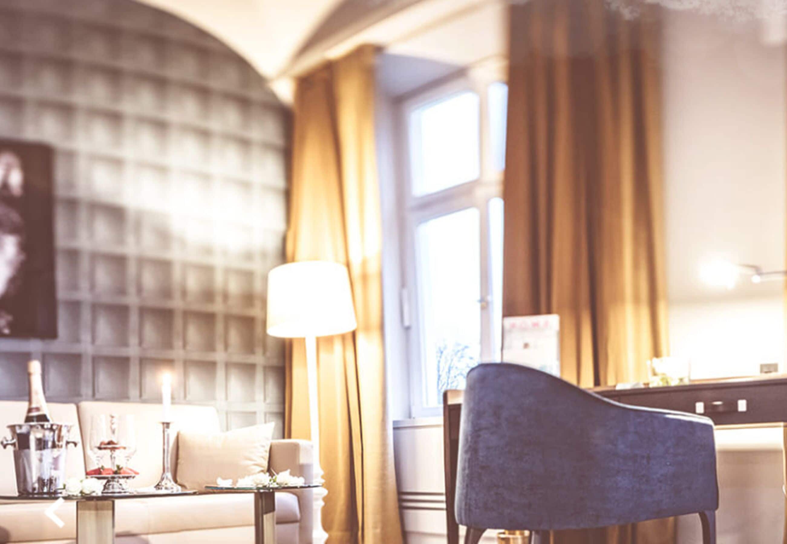 Ett hotellrum med ett stort fönster, en soffa, en lampa och en stol.