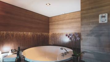A modern bathroom with a freestanding bathtub, a wall-mounted heater, and a potted orchid.