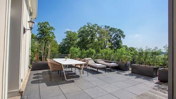An outdoor patio with a table and chairs, lounge chairs, and potted plants.