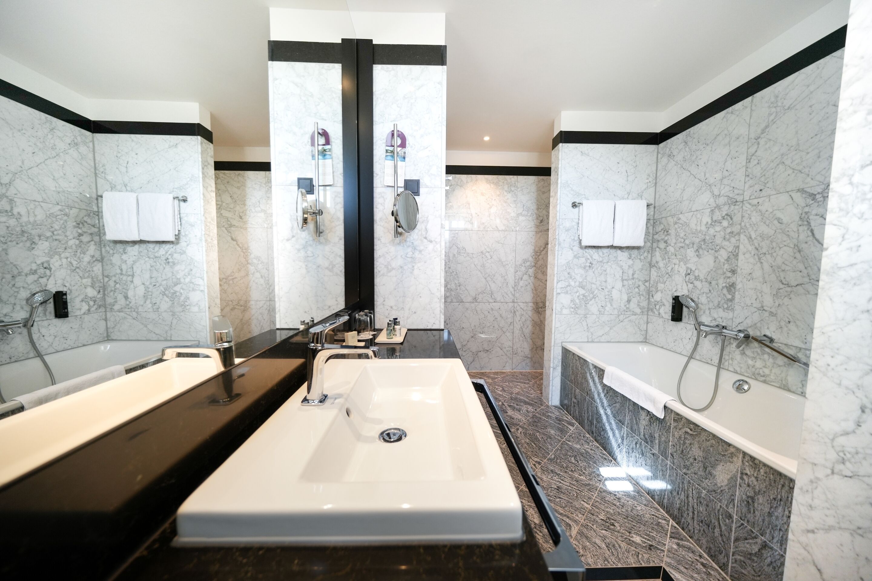 Une salle de bain moderne avec deux lavabos, un grand miroir et une baignoire.