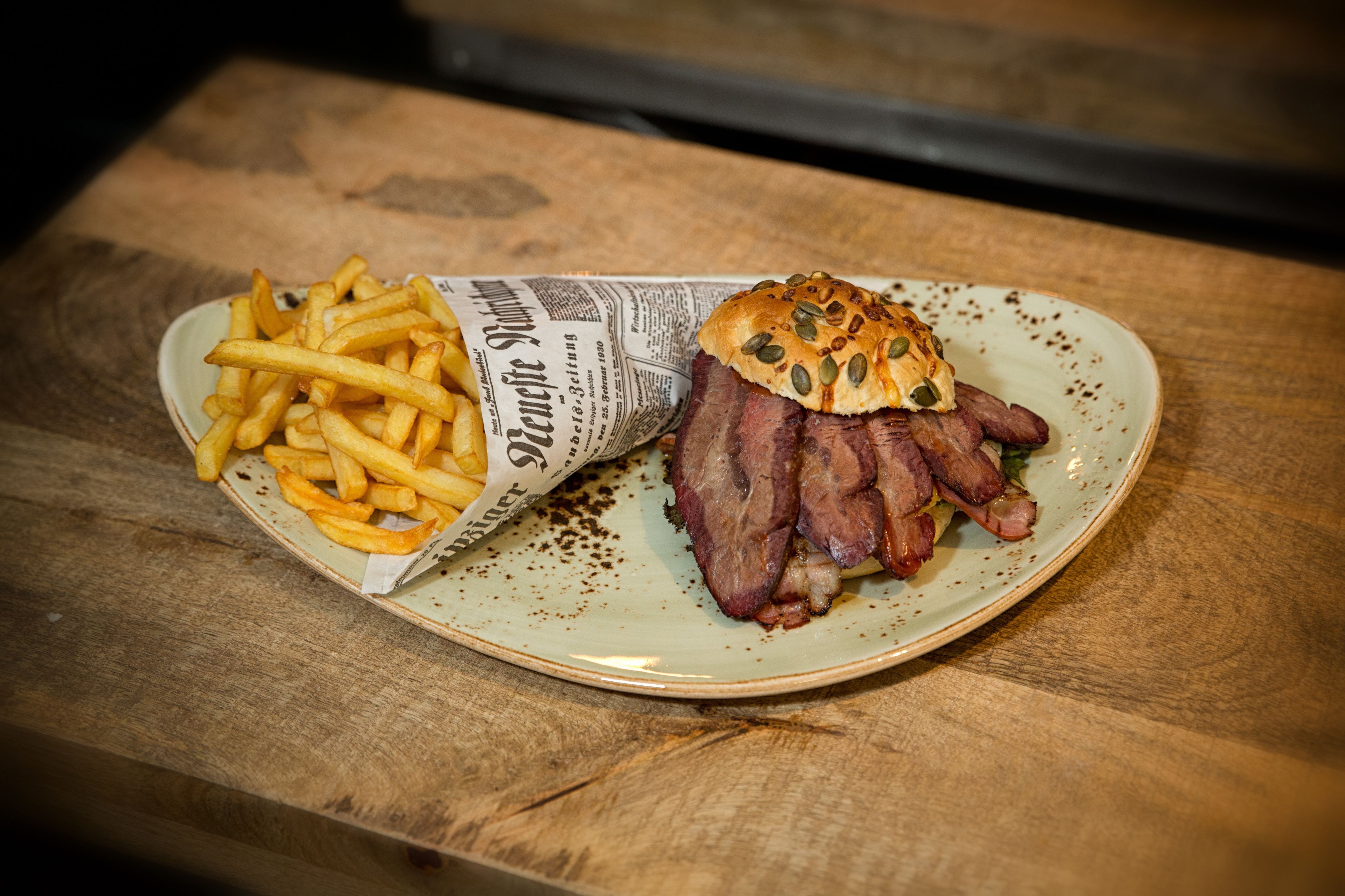 A plate with a sandwich and fries on a wooden table.