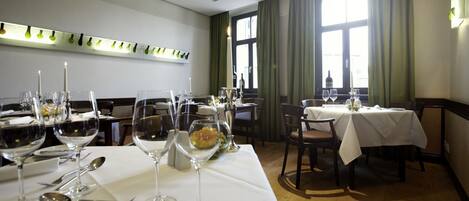 A restaurant with tables set for dining, featuring wine glasses, cutlery, and a candle centerpiece.