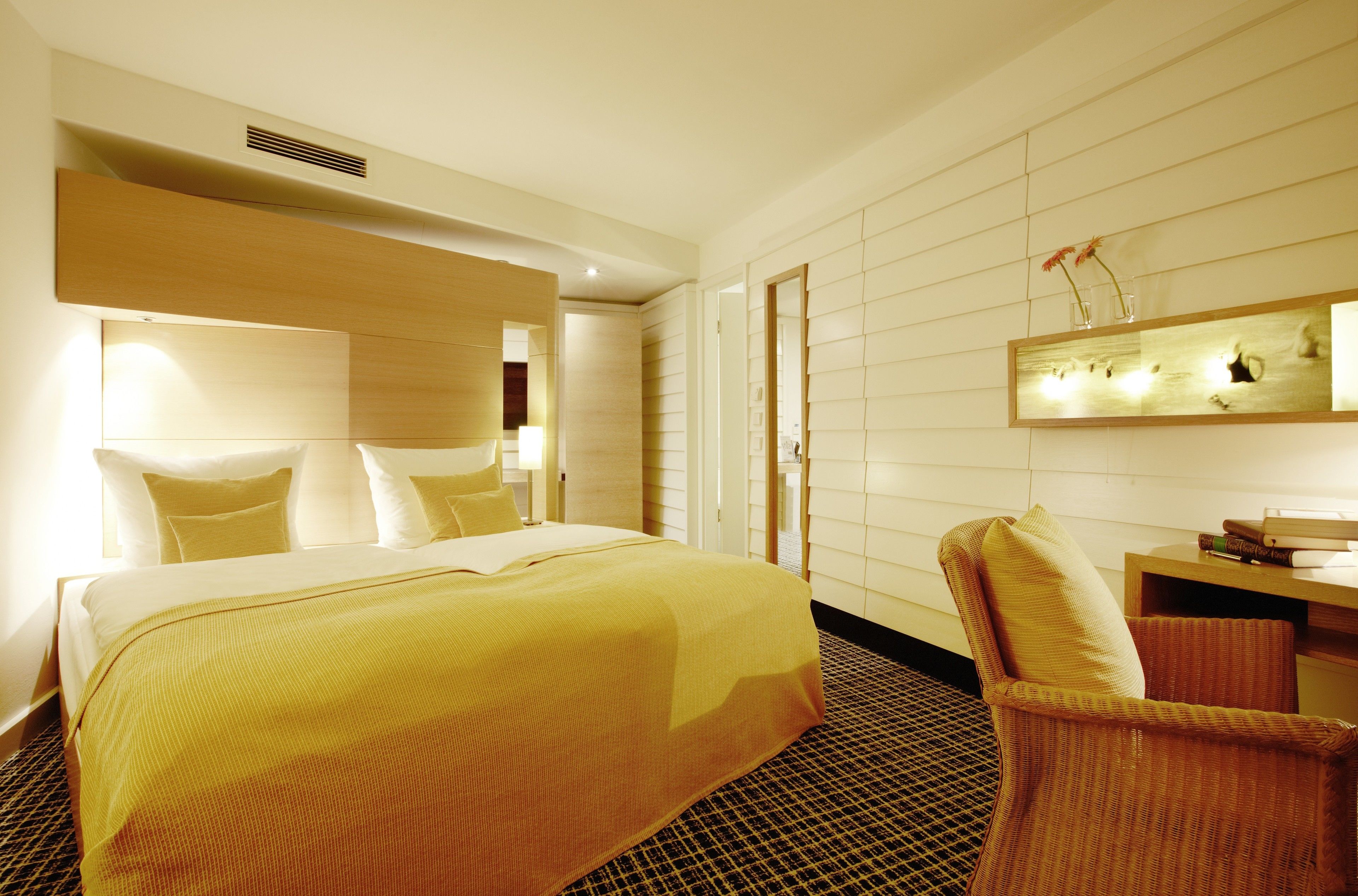 Ein Hotelzimmer mit einem großen Bett, einem Sessel, einem Schreibtisch und einem Spiegel an der Wand.