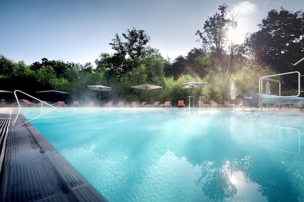 Una piscina cubierta, una piscina al aire libre, sombrillas, tumbonas