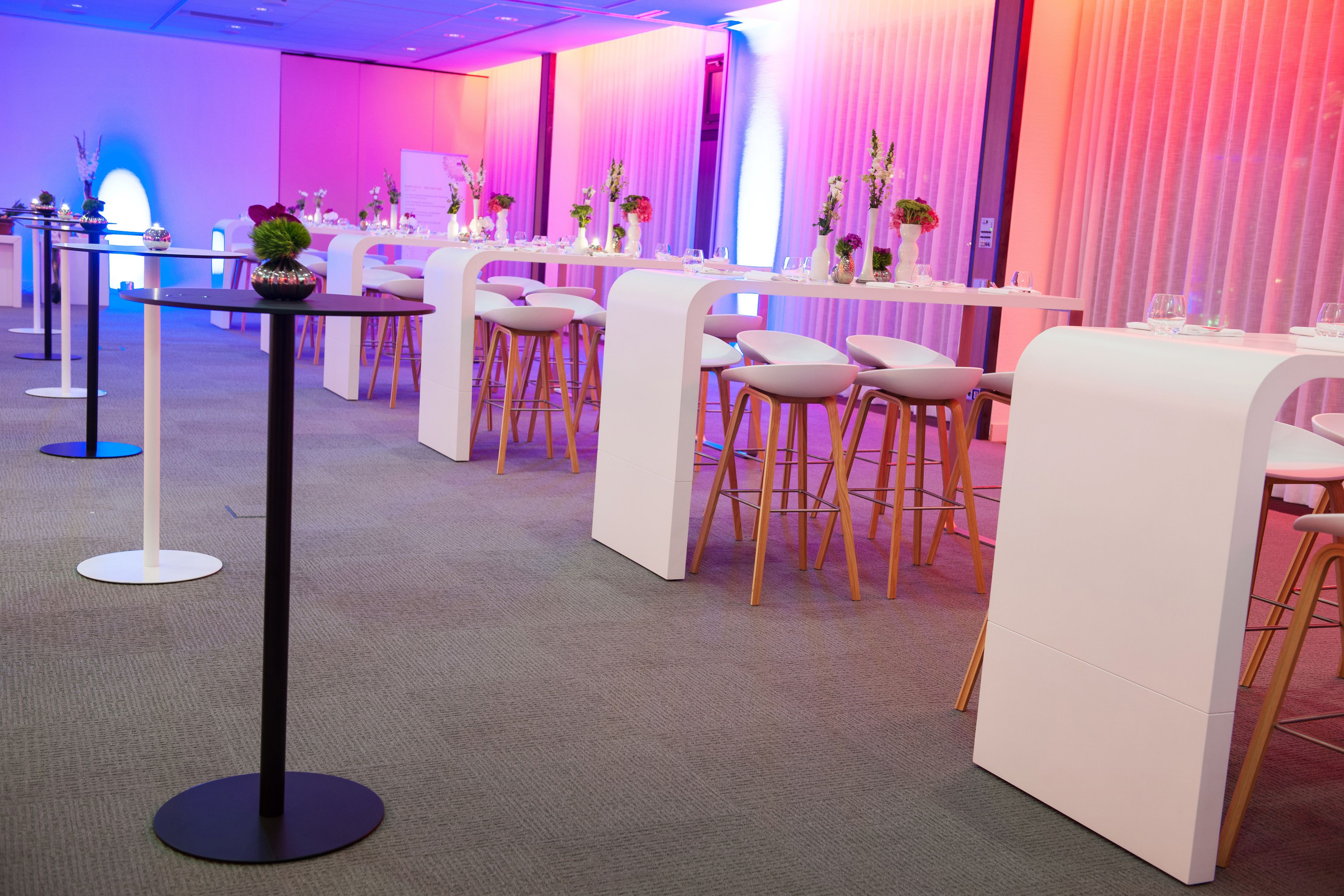 A modern hotel lobby with white furniture, a reception desk, and a blue-lit area.