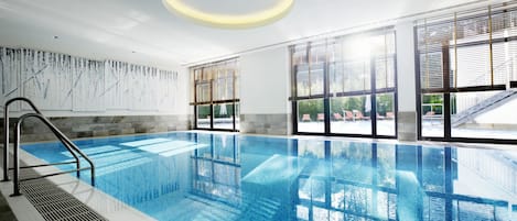 Alberca techada, alberca al aire libre y sombrillas en la alberca